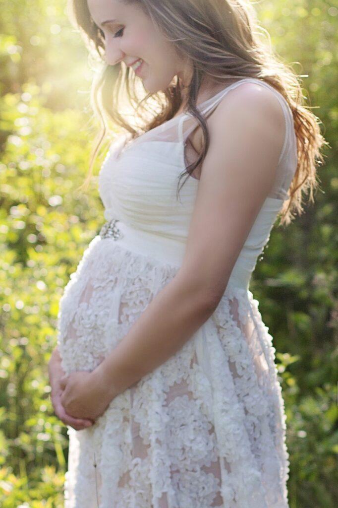 Femme enceinte en robe blanche dans la nature